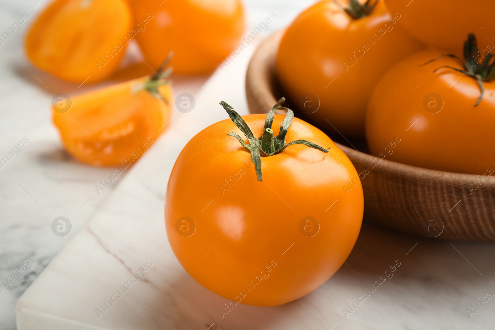 Photo of Ripe yellow tomatoes on white marble board, closeup