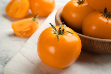 Photo of Ripe yellow tomatoes on white marble board, closeup