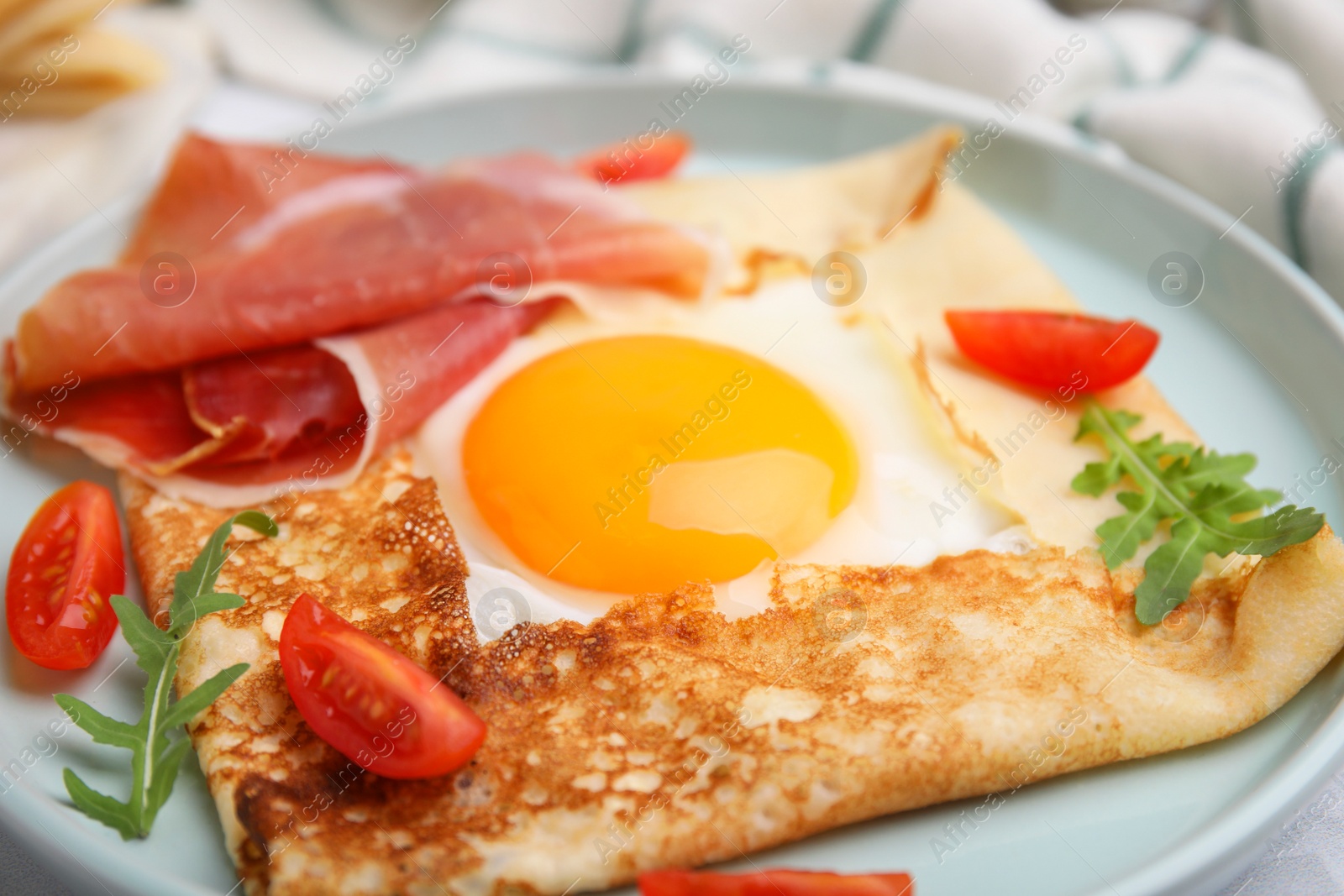 Photo of Delicious crepe with egg on plate, closeup. Breton galette