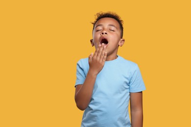 Photo of Boy yawning on yellow background. Insomnia problem