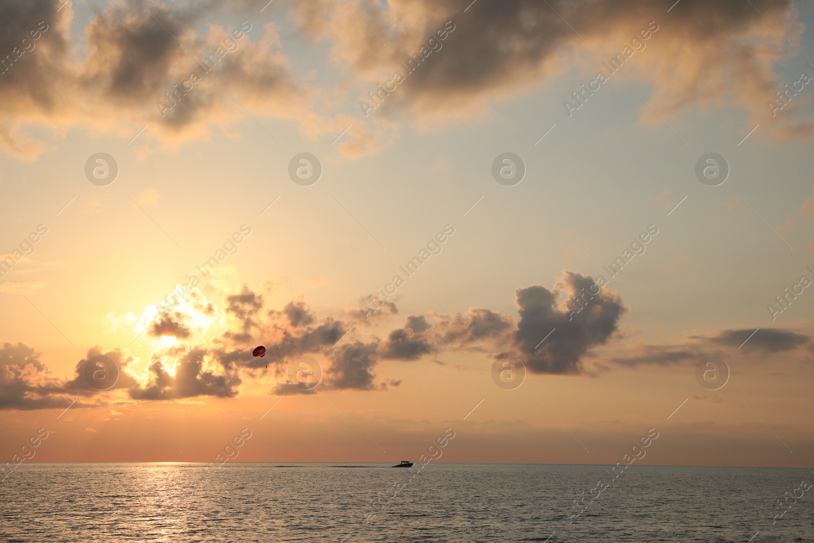 Photo of Picturesque view of beautiful sea and people parasailing at sunset