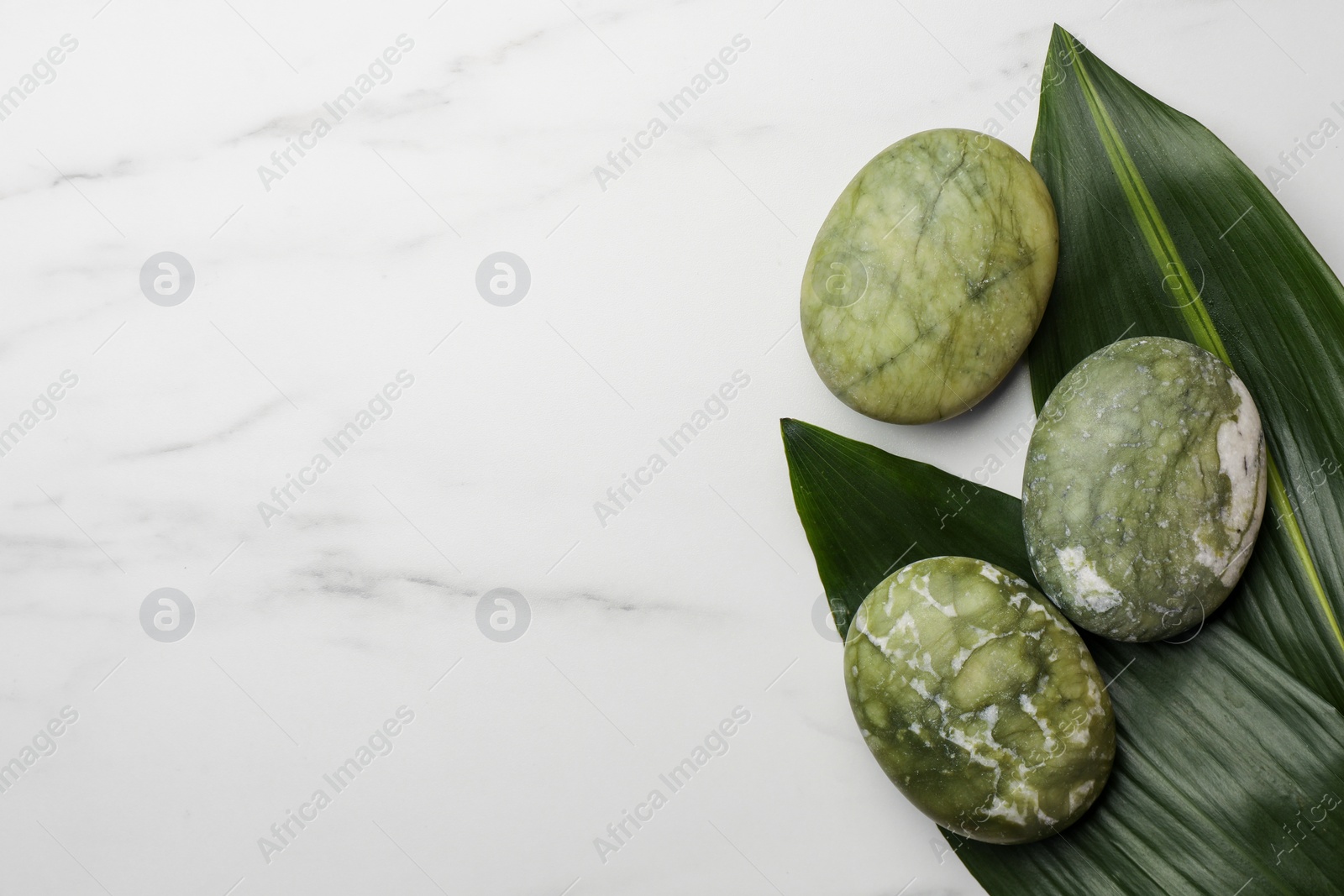 Photo of Beautiful spa composition with stones and leaves on white marble table, flat lay. Space for text