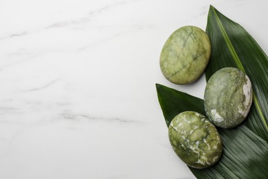 Beautiful spa composition with stones and leaves on white marble table, flat lay. Space for text