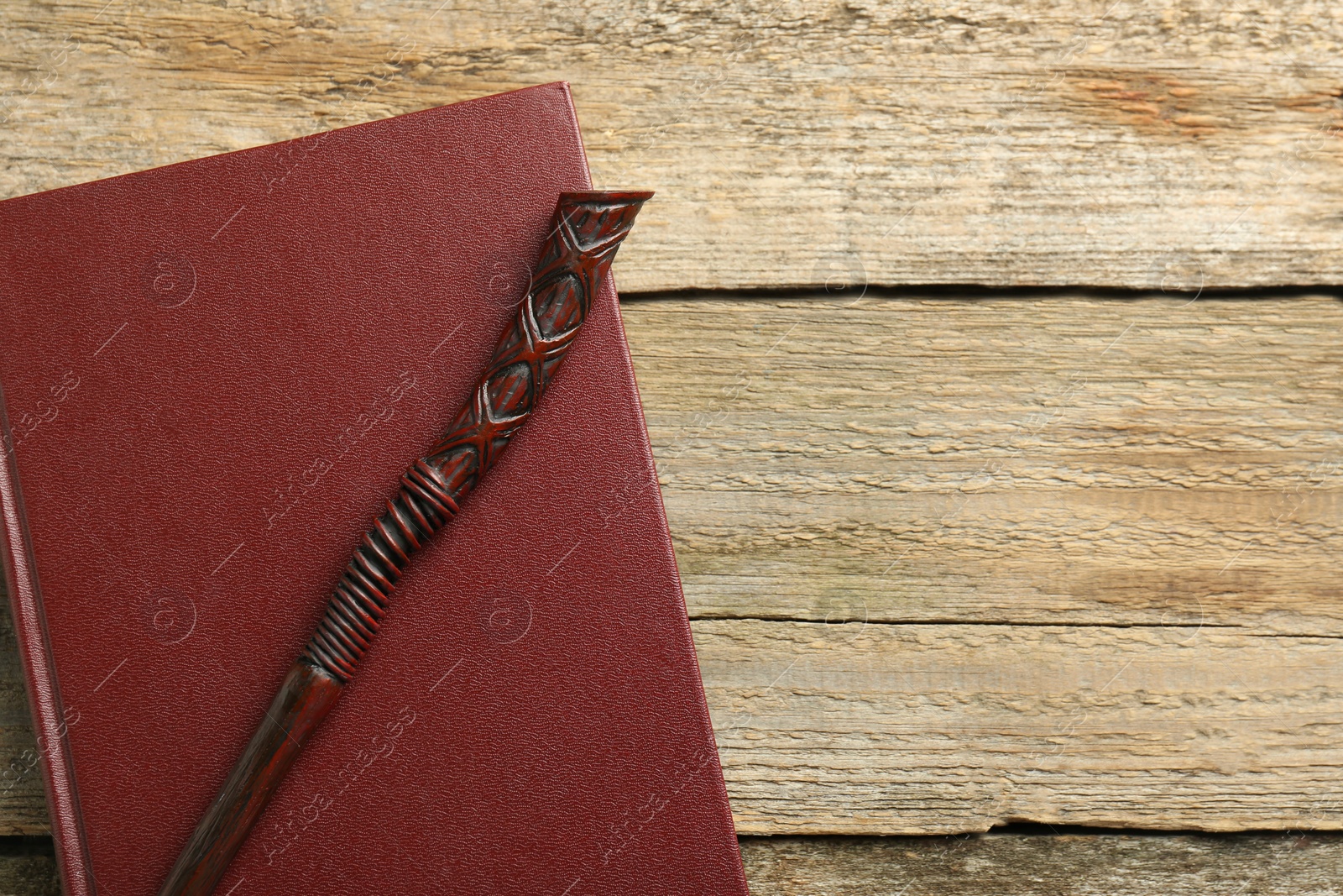 Photo of Old magic wand and book on wooden table, top view. Space for text