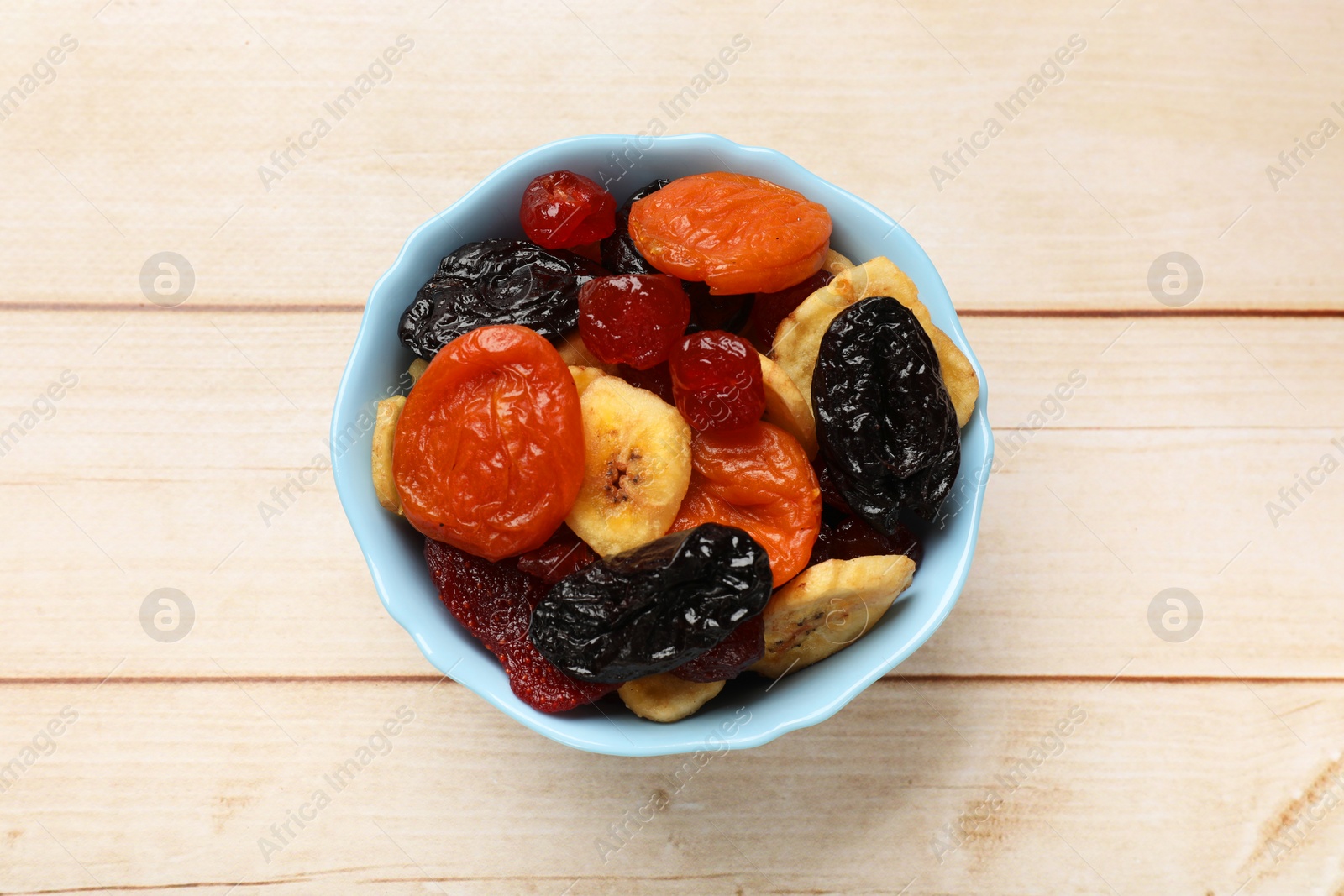 Photo of Mix of delicious dried fruits on white wooden table, top view