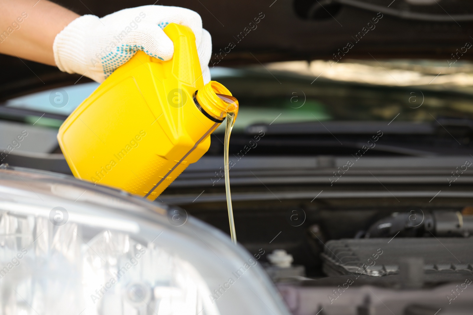 Photo of Man pouring motor oil from yellow container, closeup. Space for text