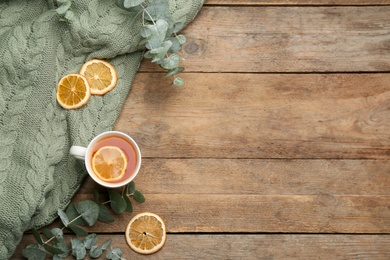 Flat lay composition with tea and warm plaid on wooden table, space for text