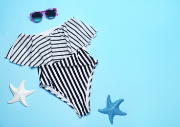 Photo of Stylish women's swimsuit with sunglasses on blue background, flat lay. Space for text