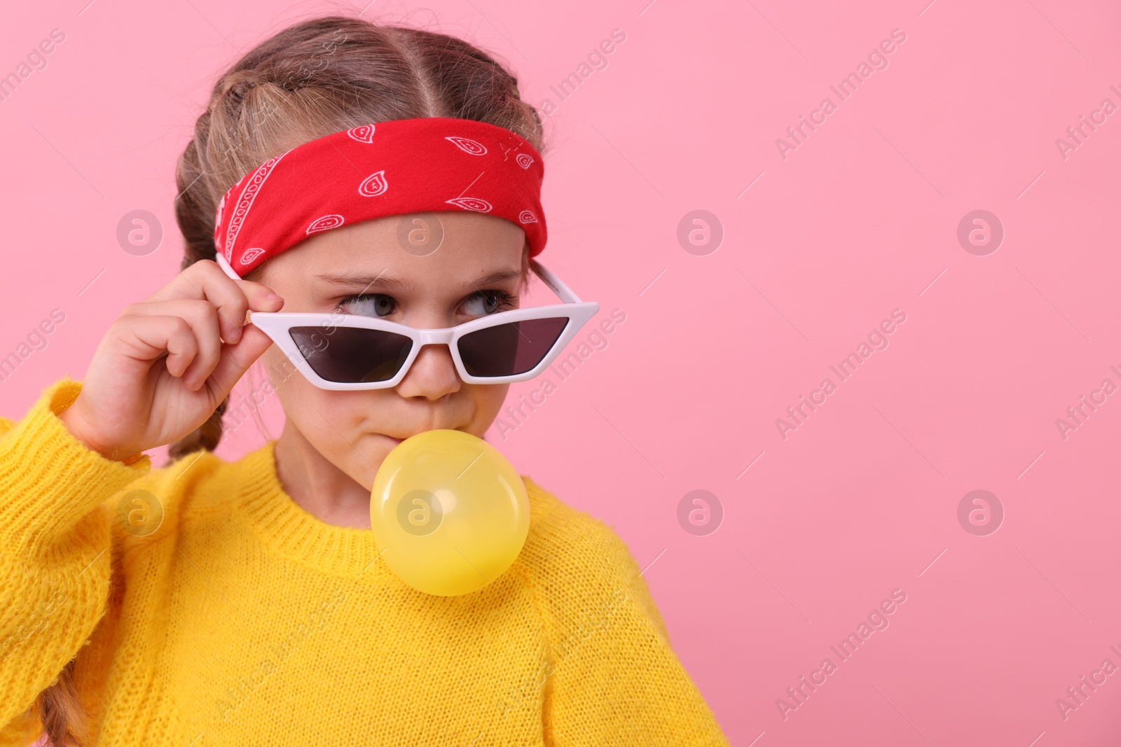 Photo of Girl in sunglasses blowing bubble gum on pink background, space for text