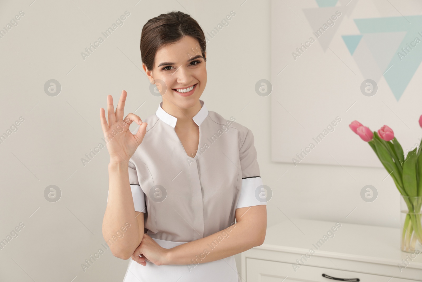 Photo of Young maid showing OK gesture in hotel room