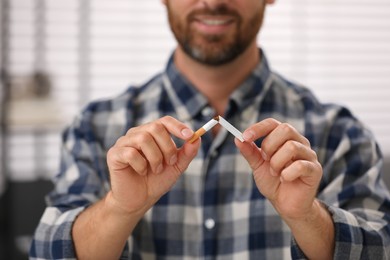 Stop smoking concept. Man breaking cigarette on blurred background, closeup