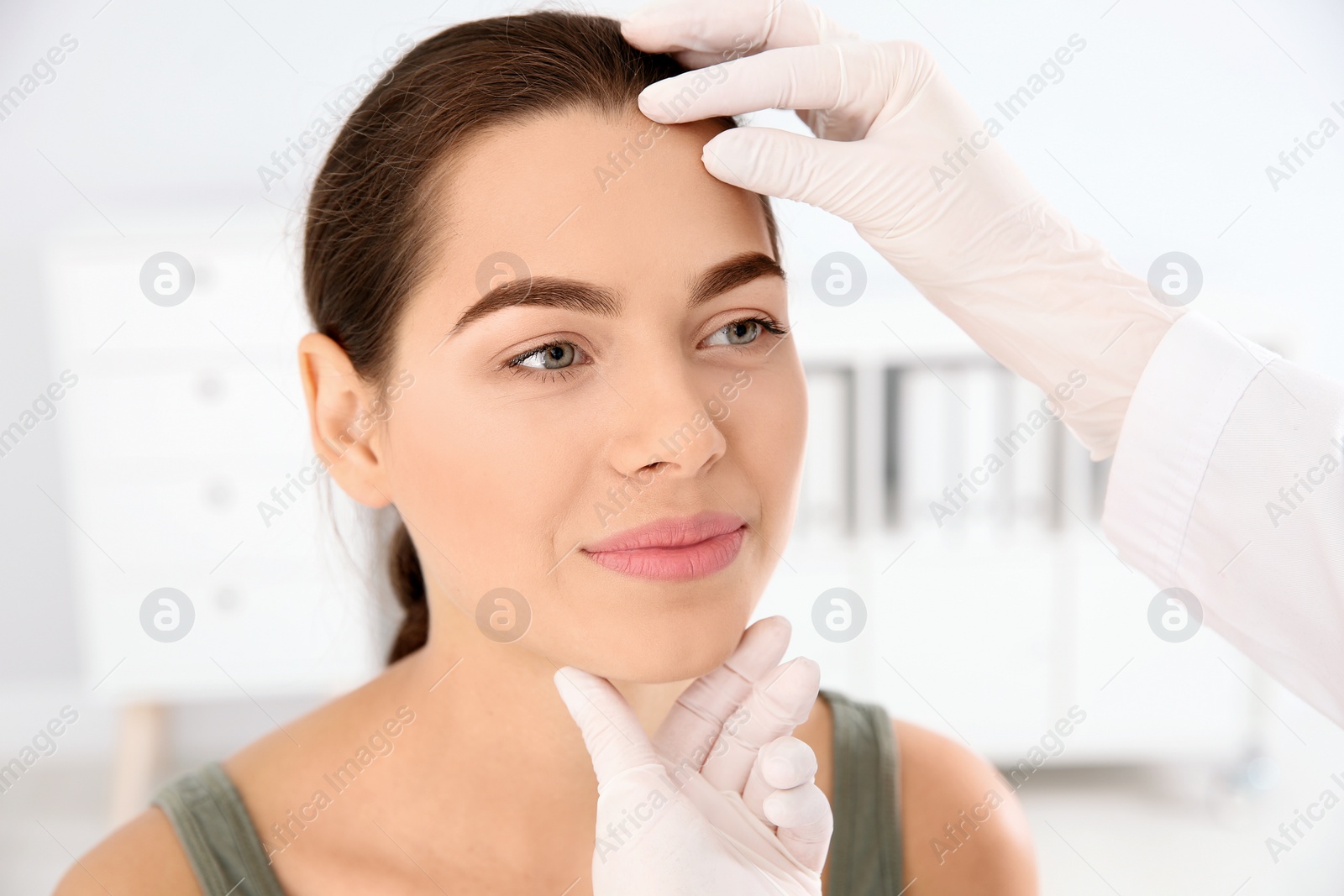 Photo of Dermatologist examining patient's face in clinic. Skin cancer checkup