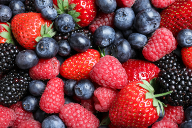 Mix of different ripe tasty berries as background, top view