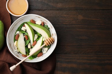 Photo of Delicious pear salad in bowl, honey and dipper on wooden table, top view. Space for text