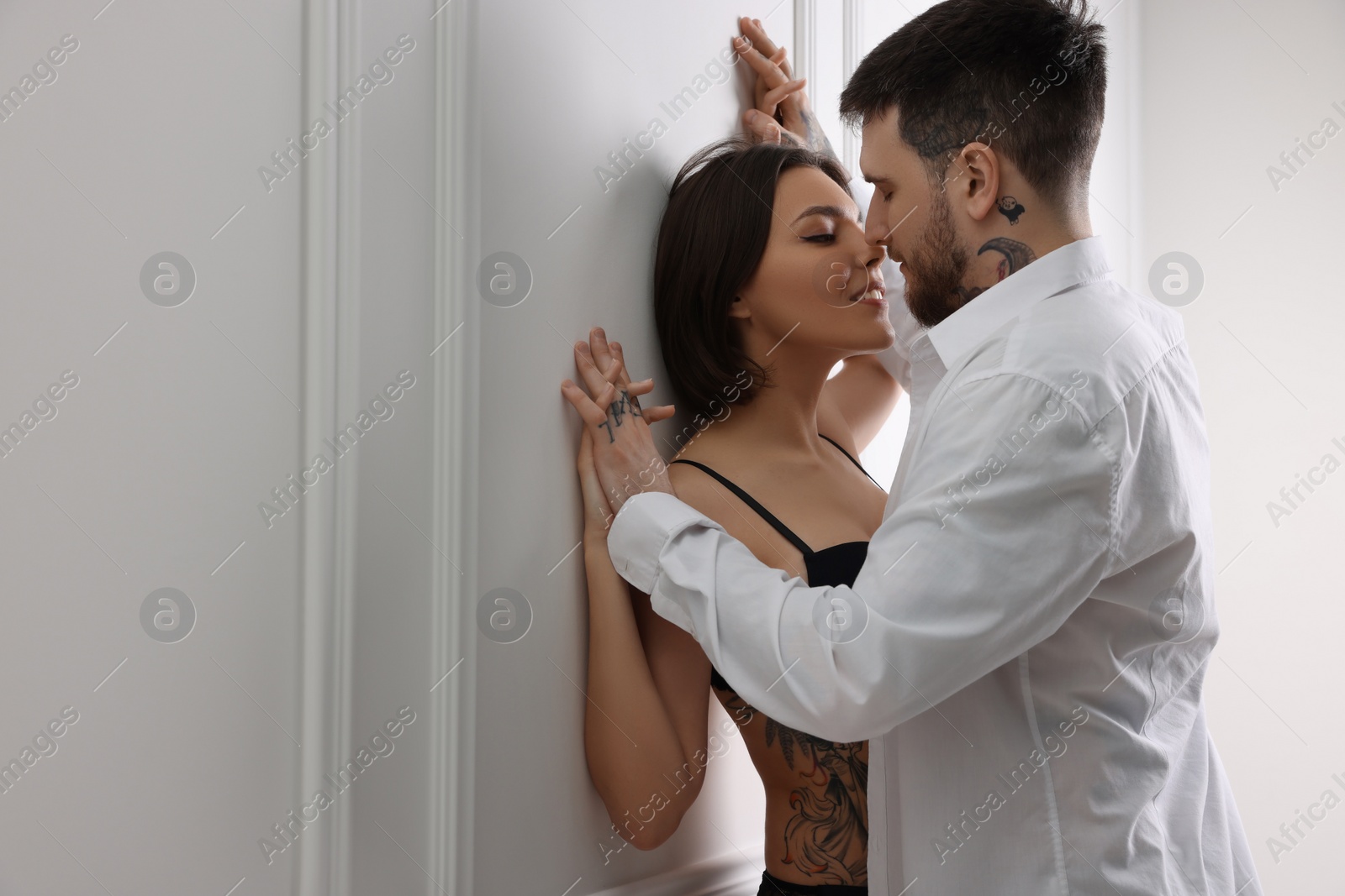 Photo of Passionate couple having sex near white wall indoors, space for text