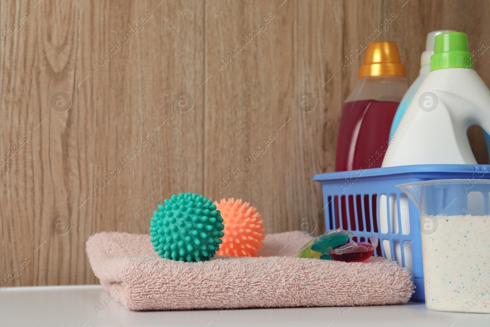 Photo of Dryer balls, detergents and clean towel on washing machine. Space for text