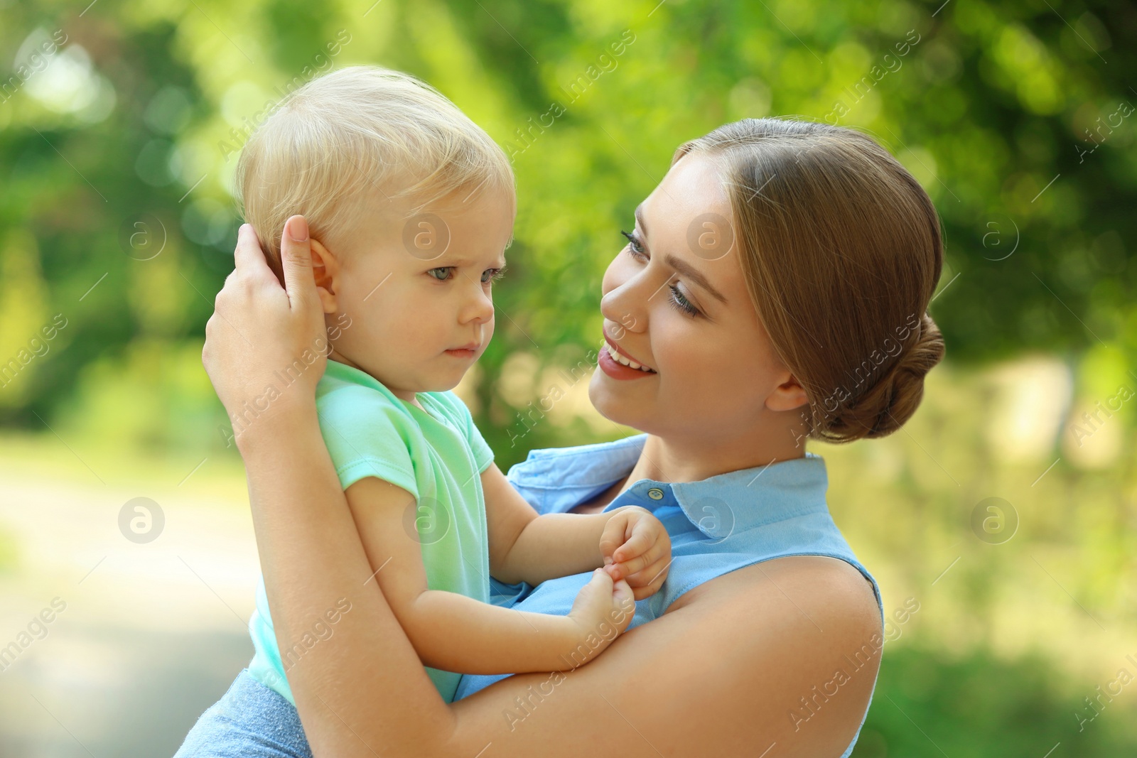 Photo of Young mother with her cute child in green park