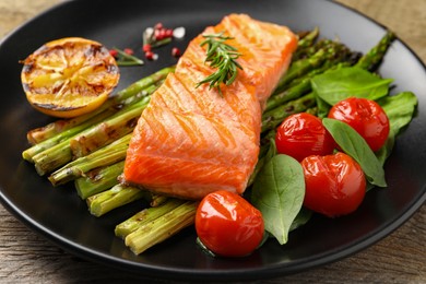 Photo of Tasty grilled salmon with tomatoes, asparagus and spices on table, closeup