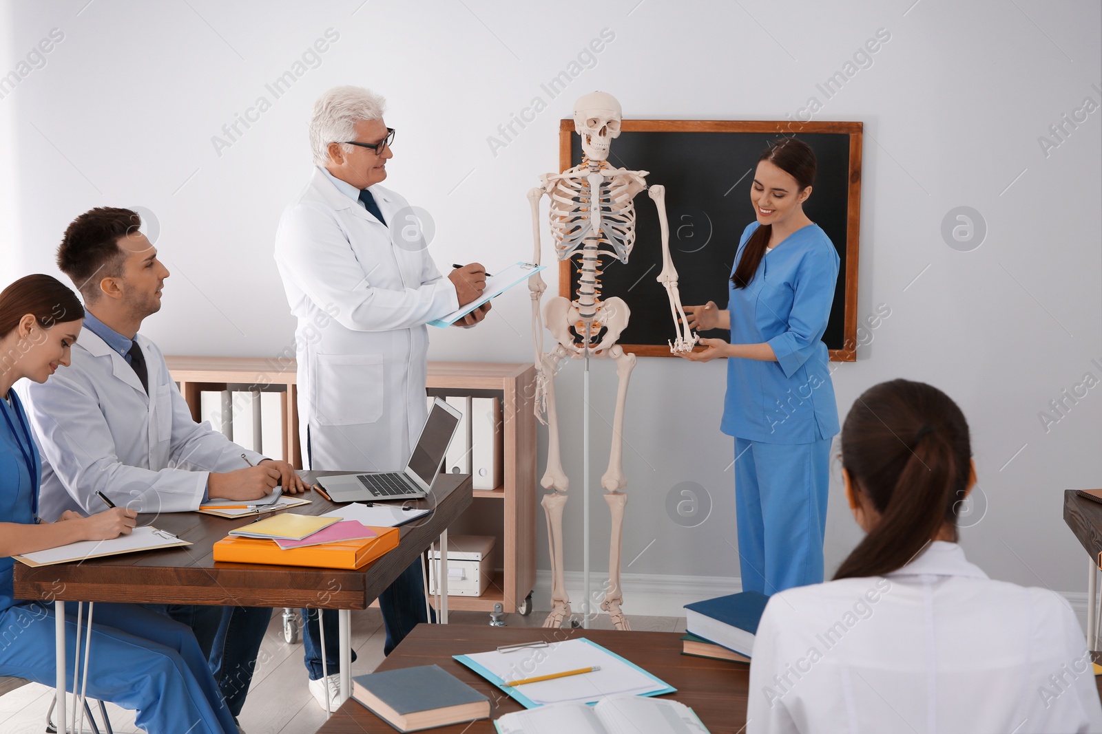 Photo of Medical students and professor studying human skeleton anatomy in classroom