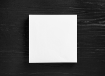 Photo of Stack of blank paper sheets for brochure on black wooden background, top view. Mock up