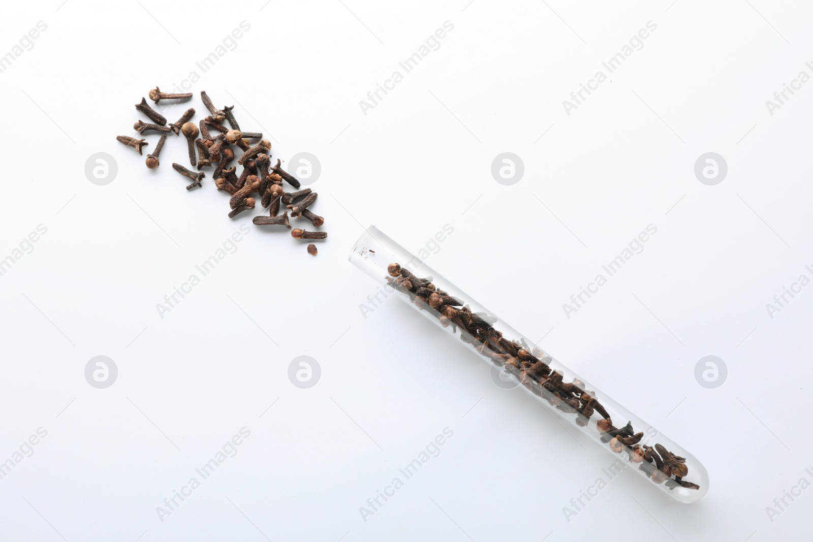 Photo of Glass tube with cloves on white background, top view