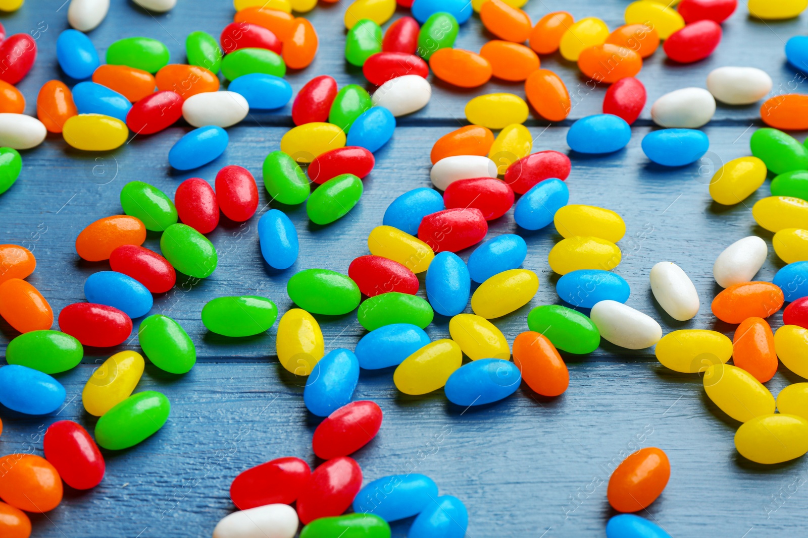 Photo of Colorful jelly beans on blue wooden background