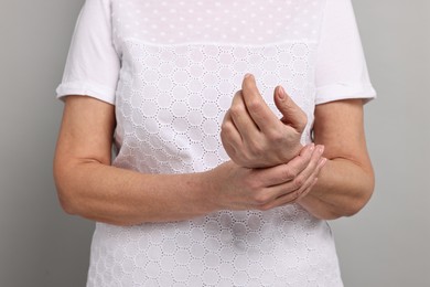 Photo of Arthritis symptoms. Woman suffering from pain in wrist on gray background, closeup