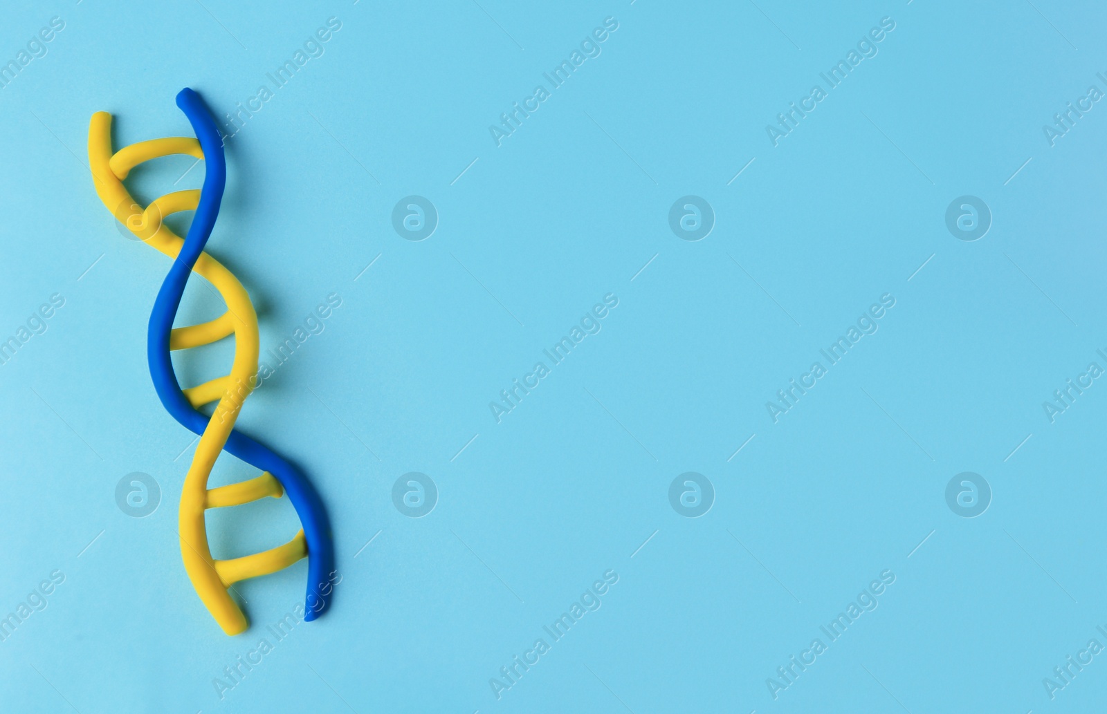 Photo of DNA molecule model made of colorful plasticine on light blue background, top view. Space for text