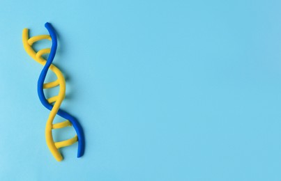 Photo of DNA molecule model madecolorful plasticine on light blue background, top view. Space for text