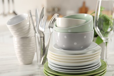 Photo of Many different clean dishware on white marble table indoors, closeup