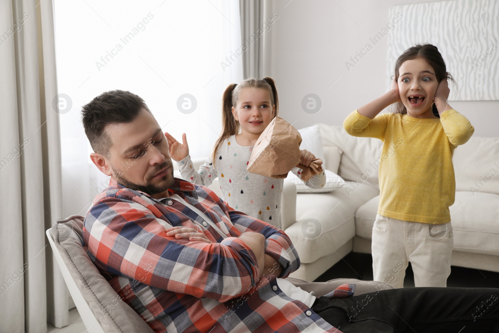 Photo of Cute little children popping paper near father while he sleeping at home