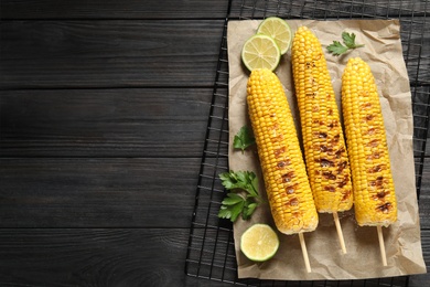 Photo of Tasty grilled corn on wooden table, flat lay. Space for text
