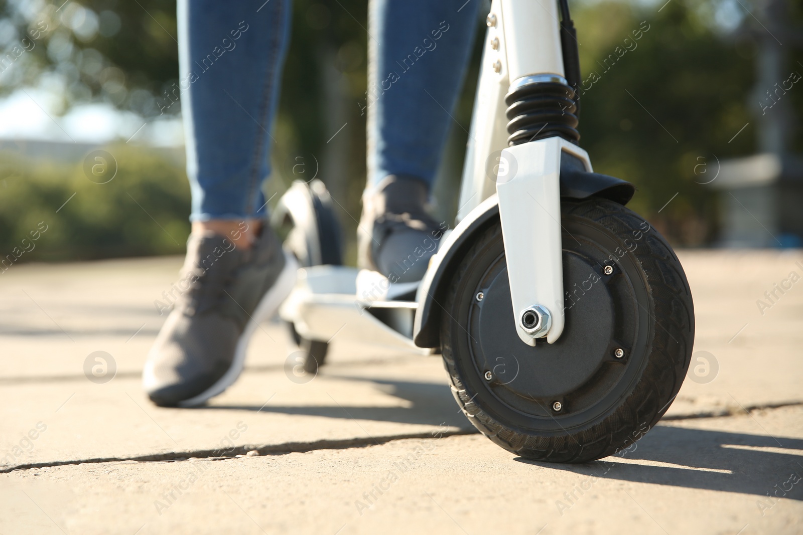 Photo of Woman riding electric kick scooter outdoors, closeup