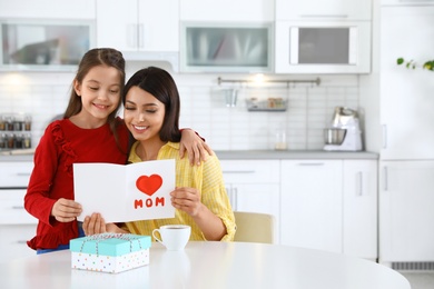 Photo of Daughter congratulating her mom in kitchen, space for text. Happy Mother's Day
