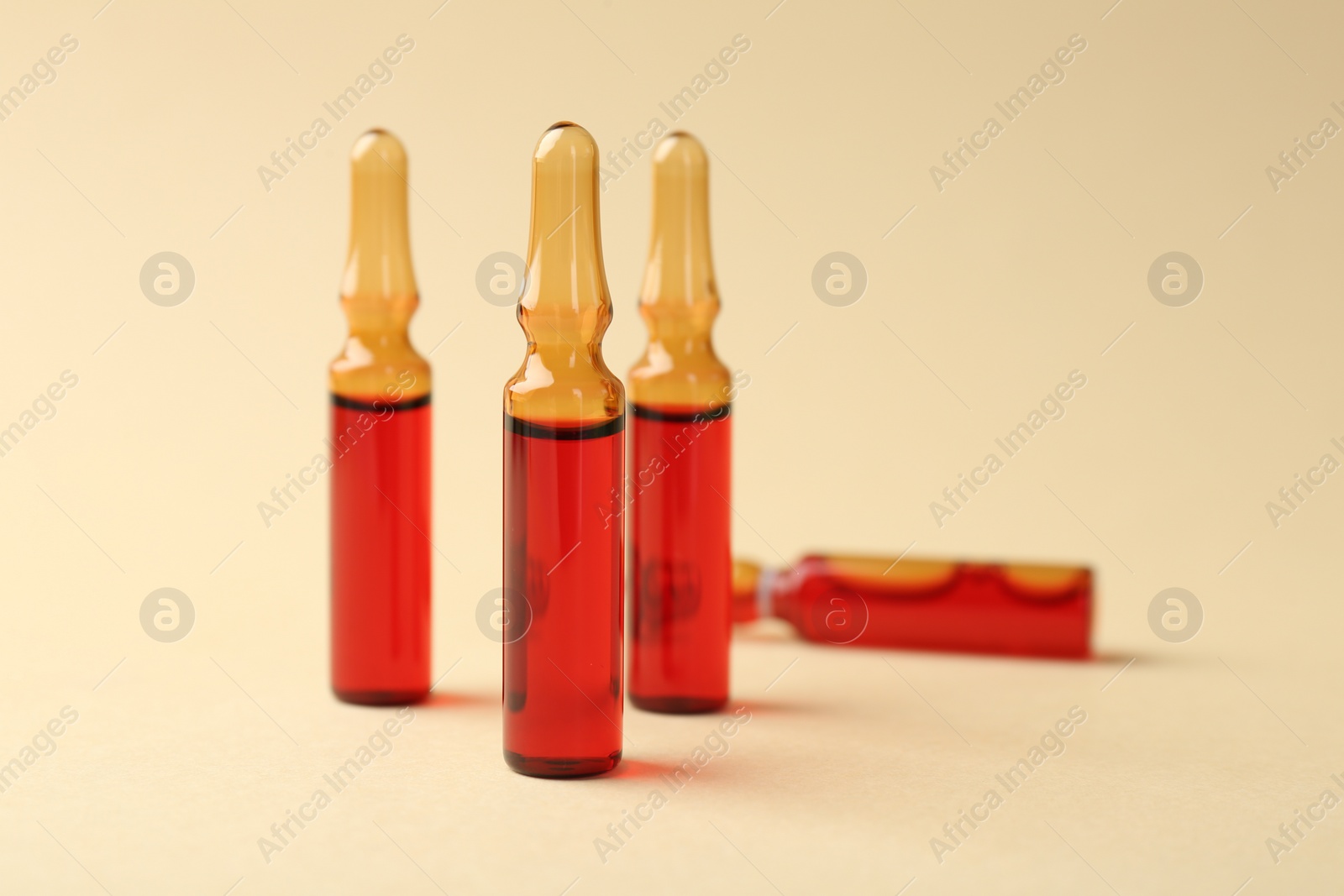 Photo of Glass ampoules with liquid on beige background