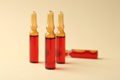 Photo of Glass ampoules with liquid on beige background