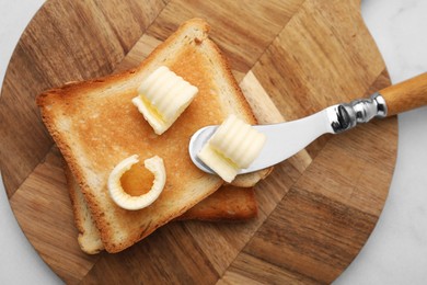 Tasty butter curls, knife and toasts on white table, top view