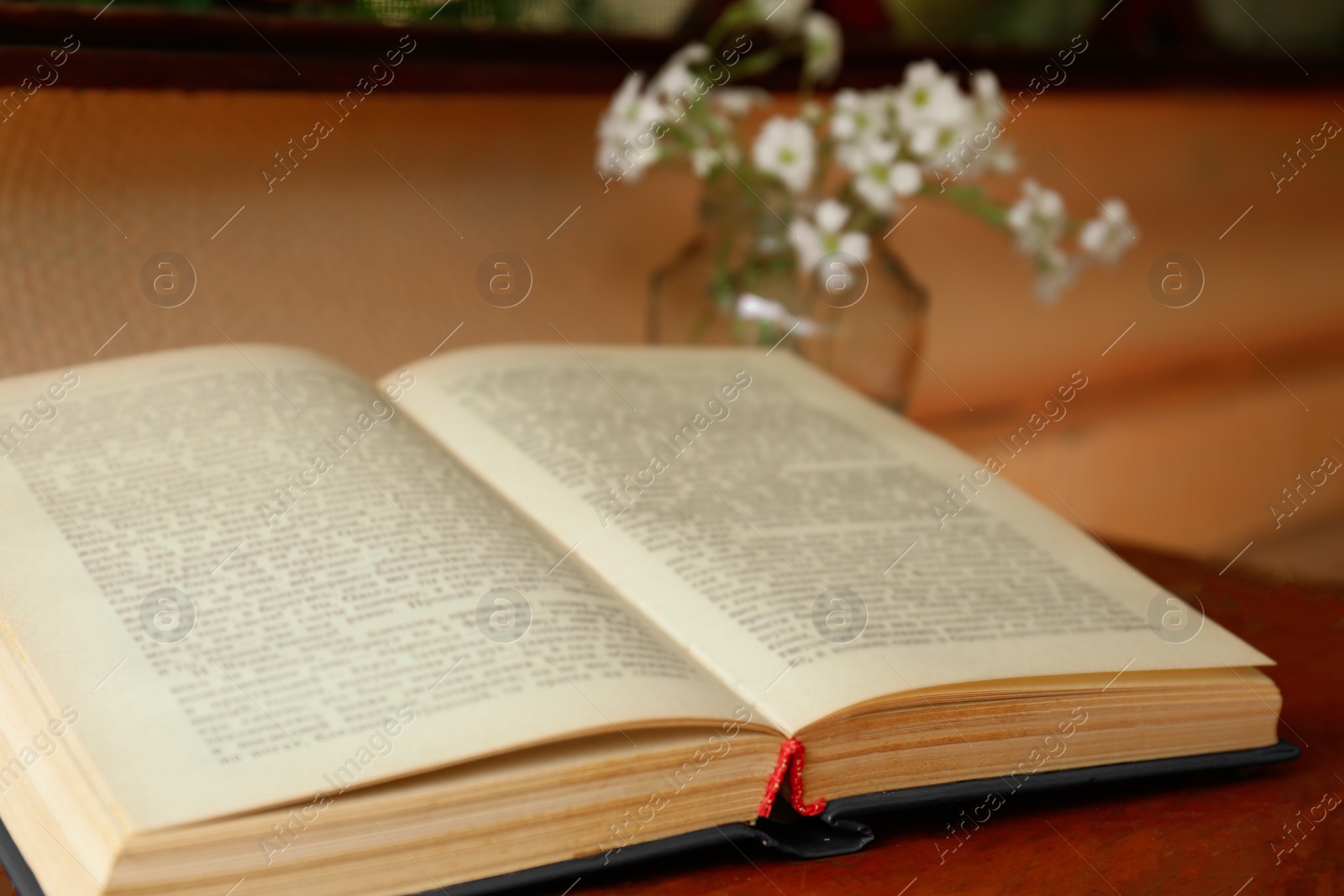 Photo of Open book and beautiful white flowers on wooden table, closeup