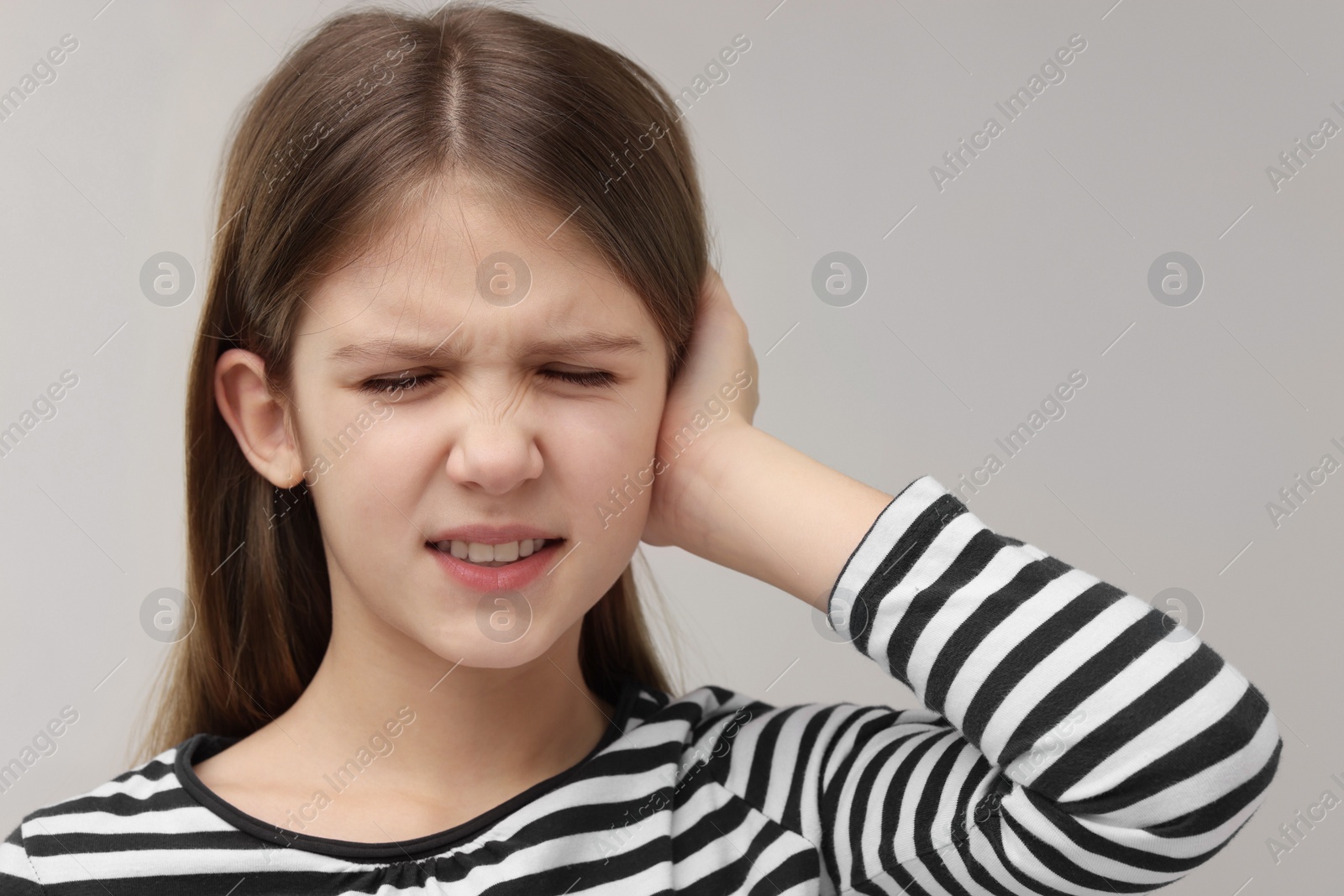 Photo of Hearing problem. Little girl suffering from ear pain on grey background