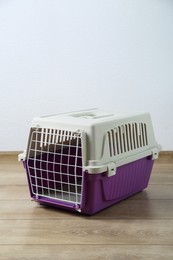 Photo of Violet pet carrier on floor near white wall