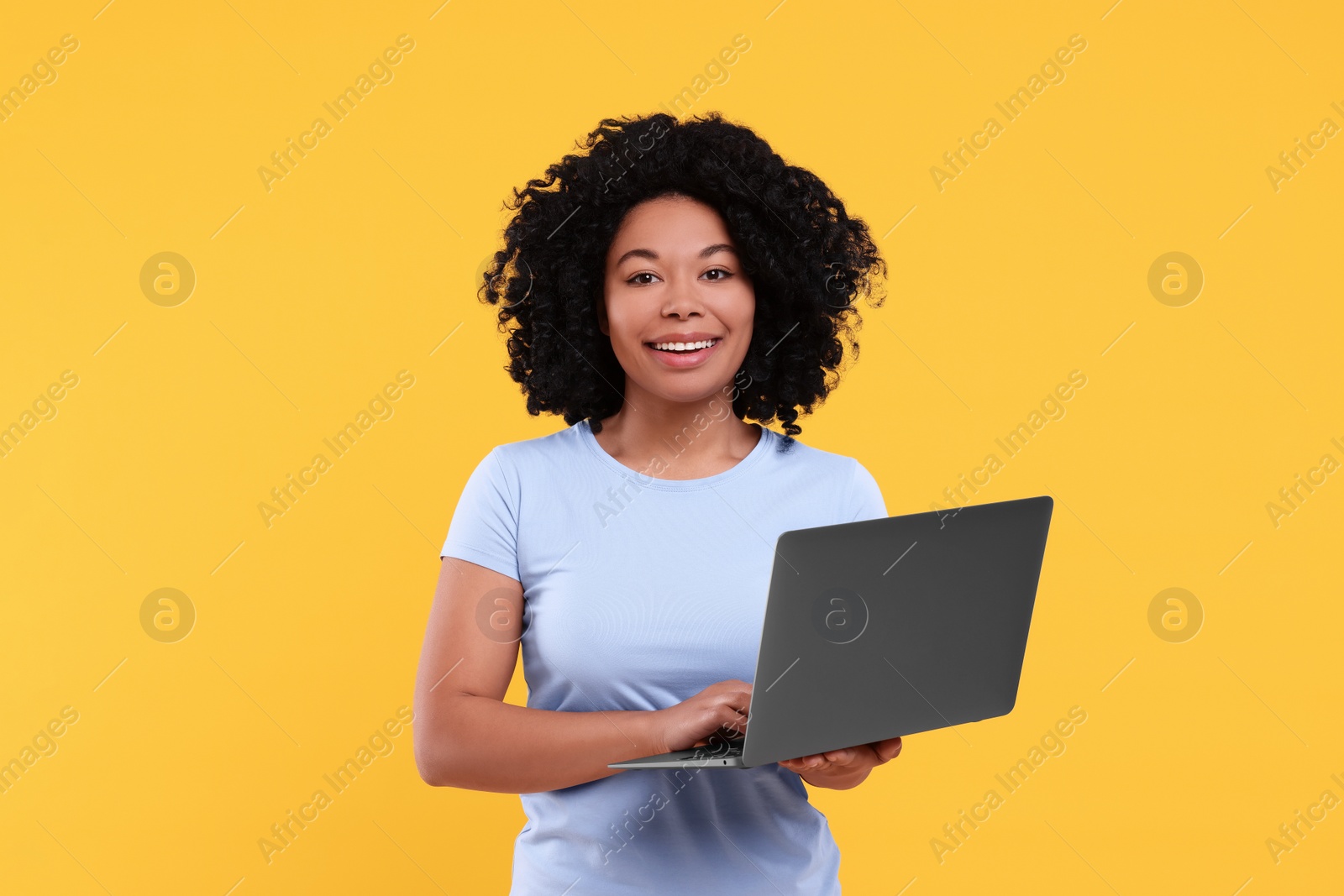 Photo of Happy young woman with laptop on yellow background