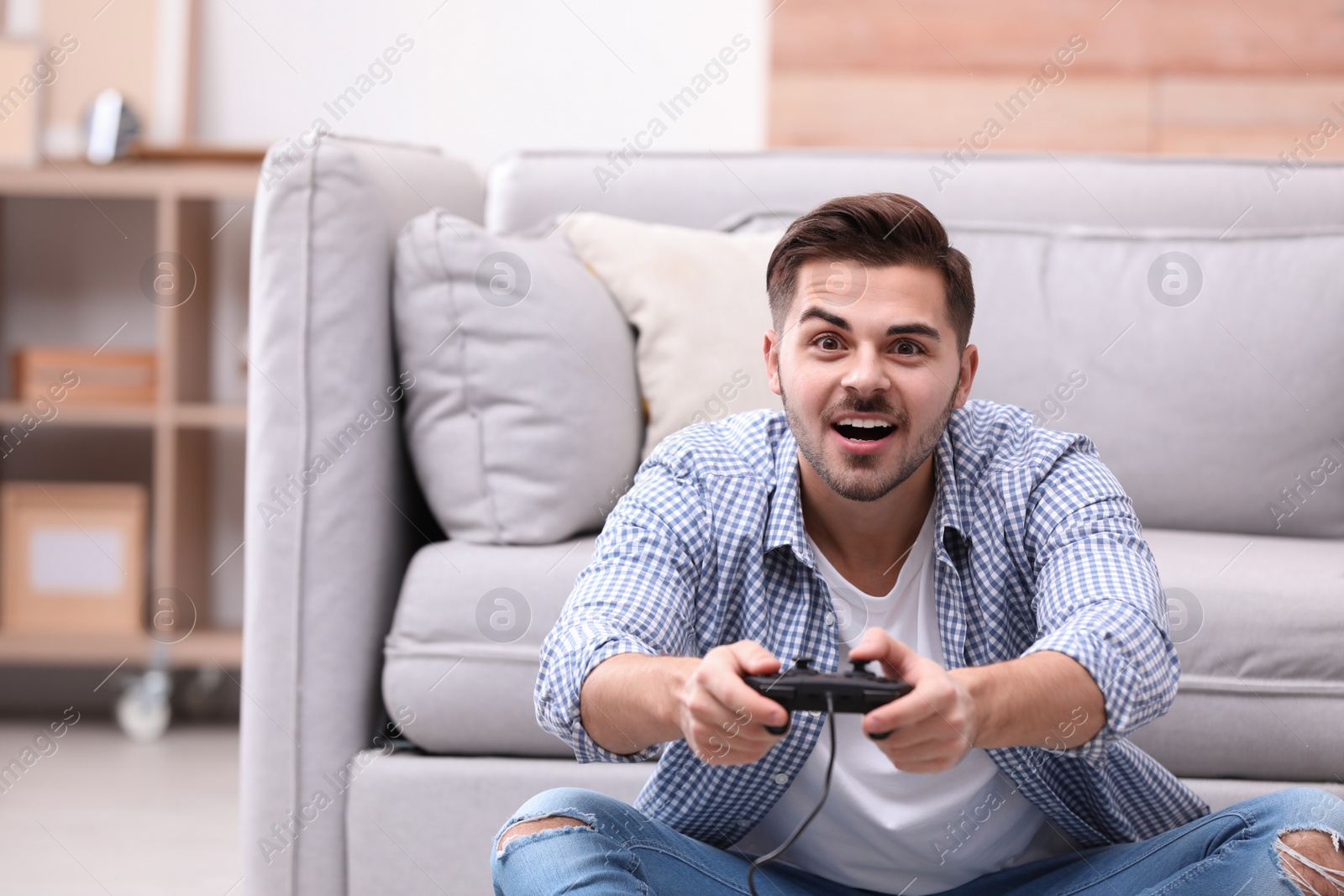 Photo of Emotional young man playing video games at home