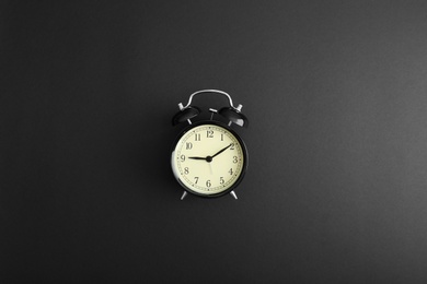 Photo of Modern alarm clock on black background, top view