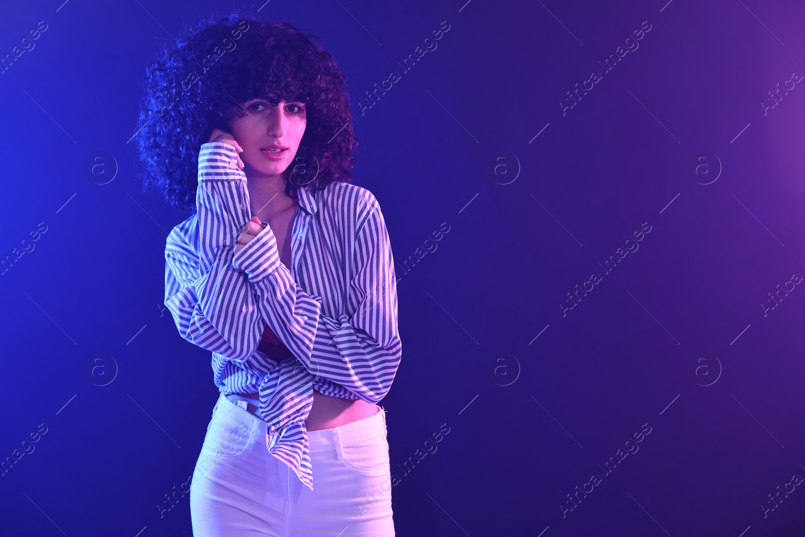 Photo of Beautiful young woman posing on color background in neon lights. Space for text