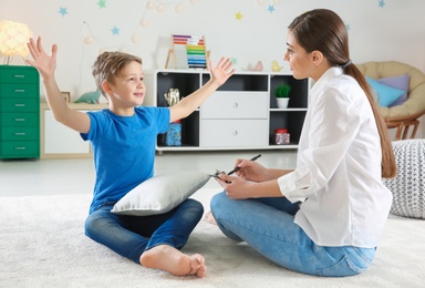 Female psychologist working with cute little boy in office