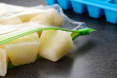 Photo of Frozen cauliflower puree cubes in plastic bag on grey table, closeup