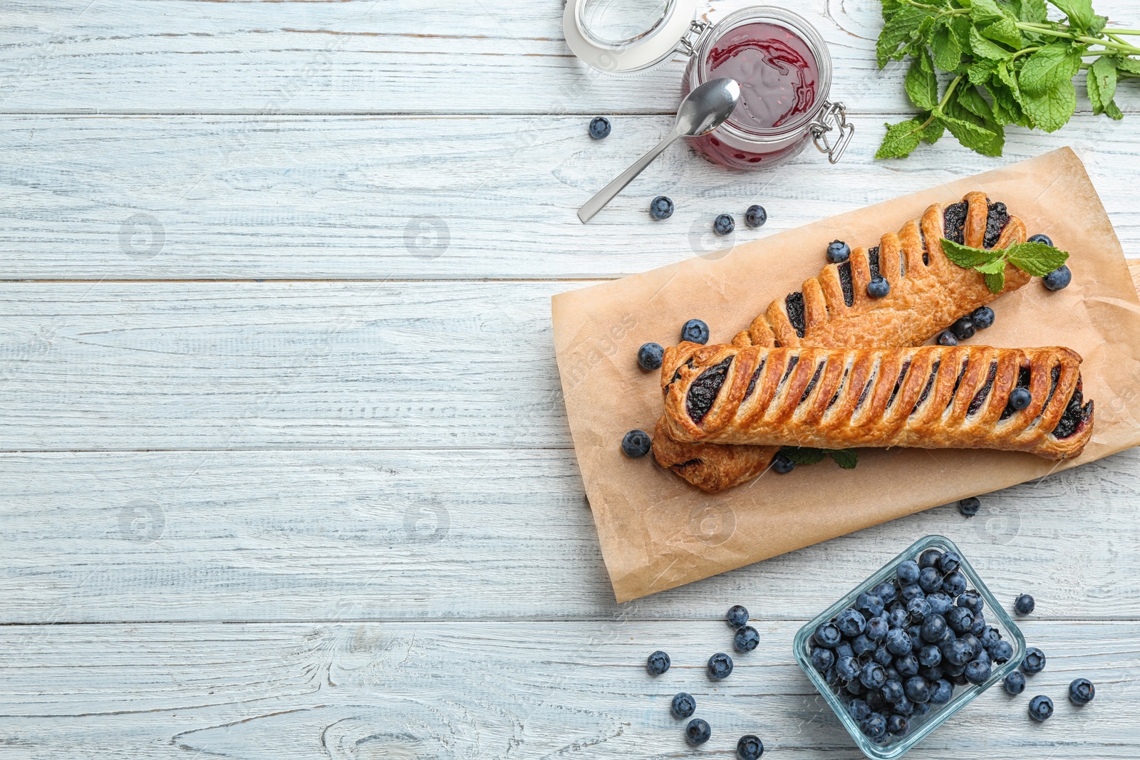 Photo of Flat lay composition with fresh delicious puff pastry on white wooden table. Space for text