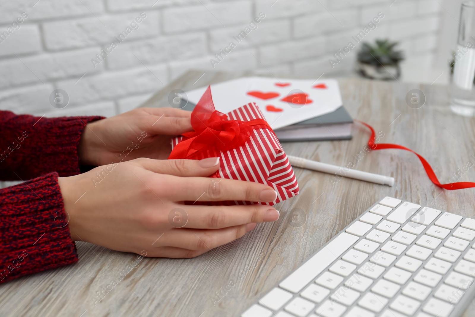 Photo of Woman with gift box at workplace, closeup. Valentine's Day celebration