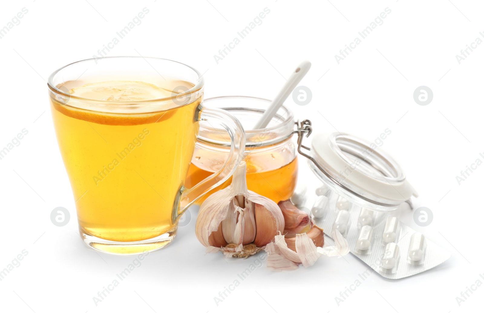 Photo of Cup with hot tea, honey, garlic and pills as cold remedies on white background