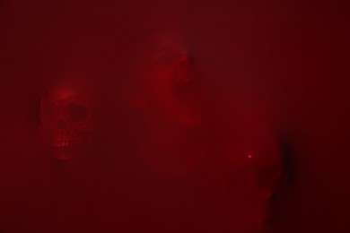 Silhouette of creepy ghost with skulls behind red cloth